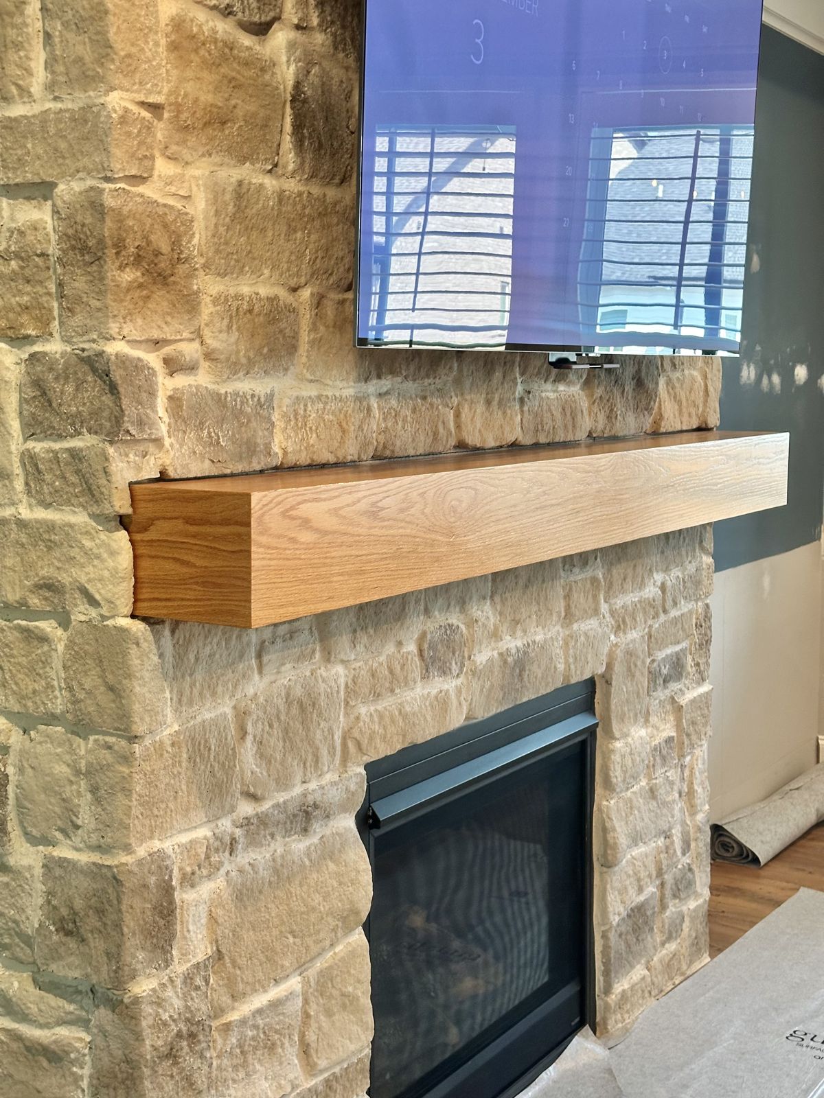 Custom oak mantel on stone fireplace