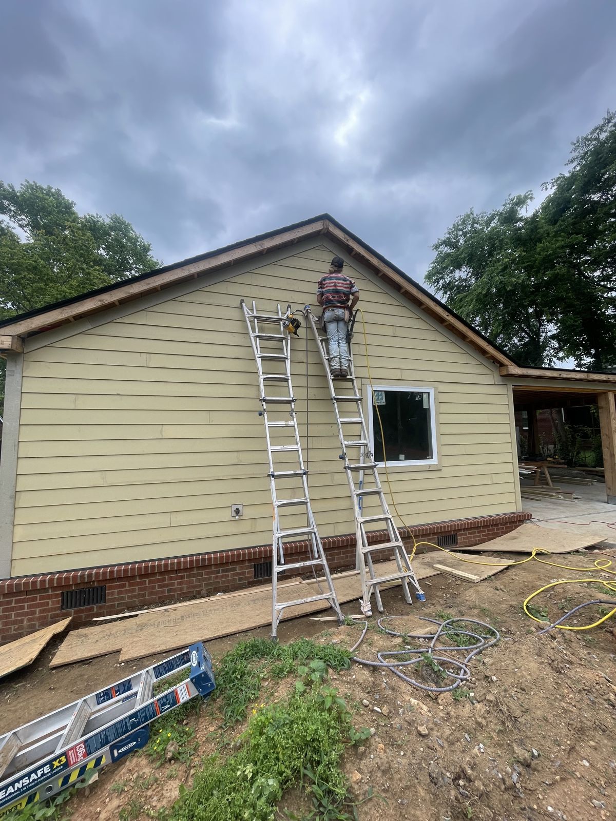 Gabriel installing lap siding on a ladder