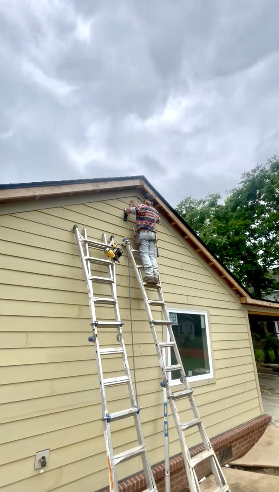 Gabriel installing siding near the roofline
